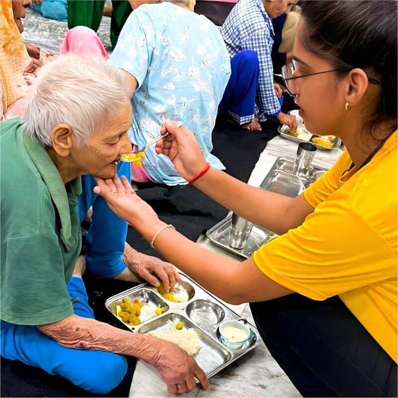 CHF volunteer feeding food to old lady